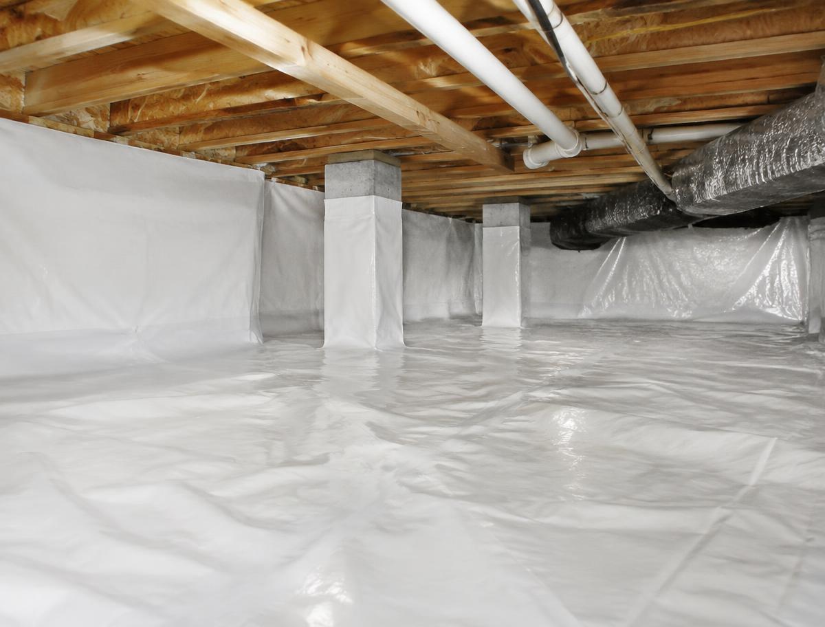 A crawl space lined with a bright white vapor barrier across the floor and walls